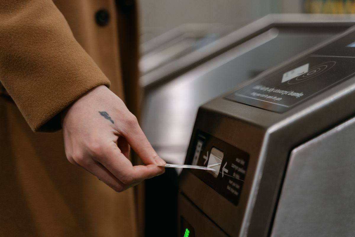 A close-up of a person inserting a ticket into a turnstile at a train station