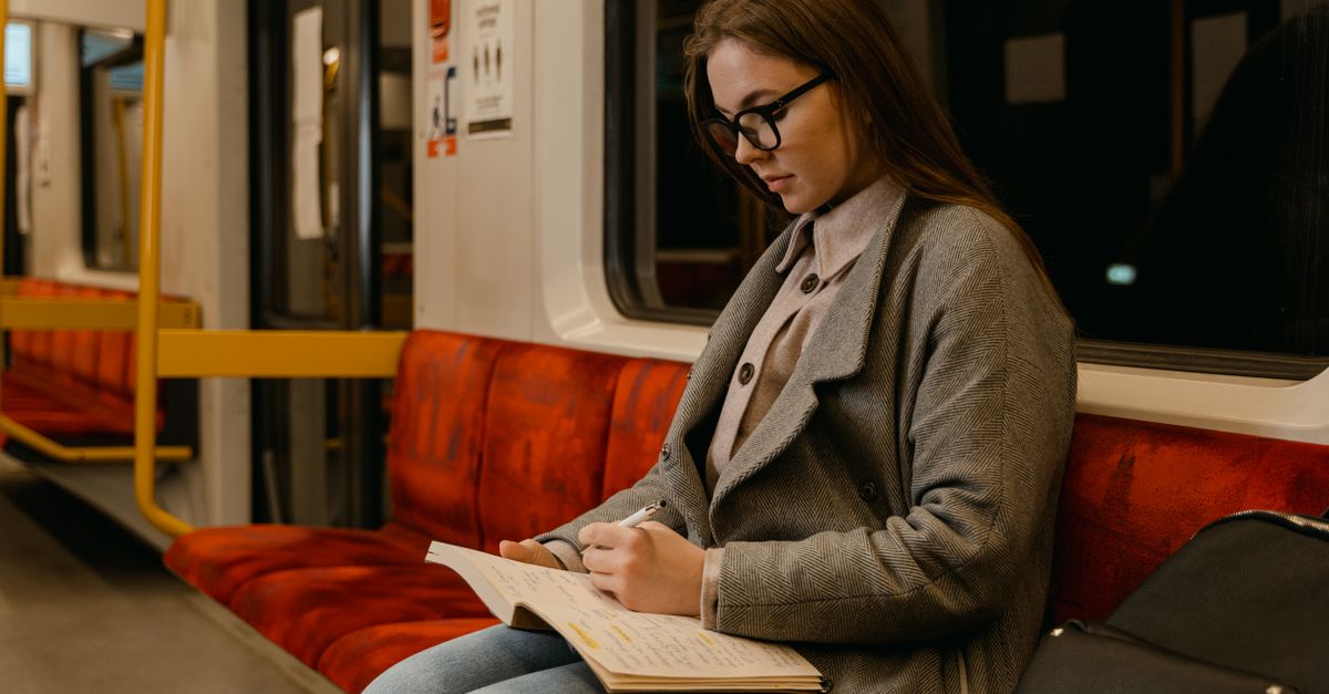 A young woman focusing on her studies while traveling on a quiet train ride.