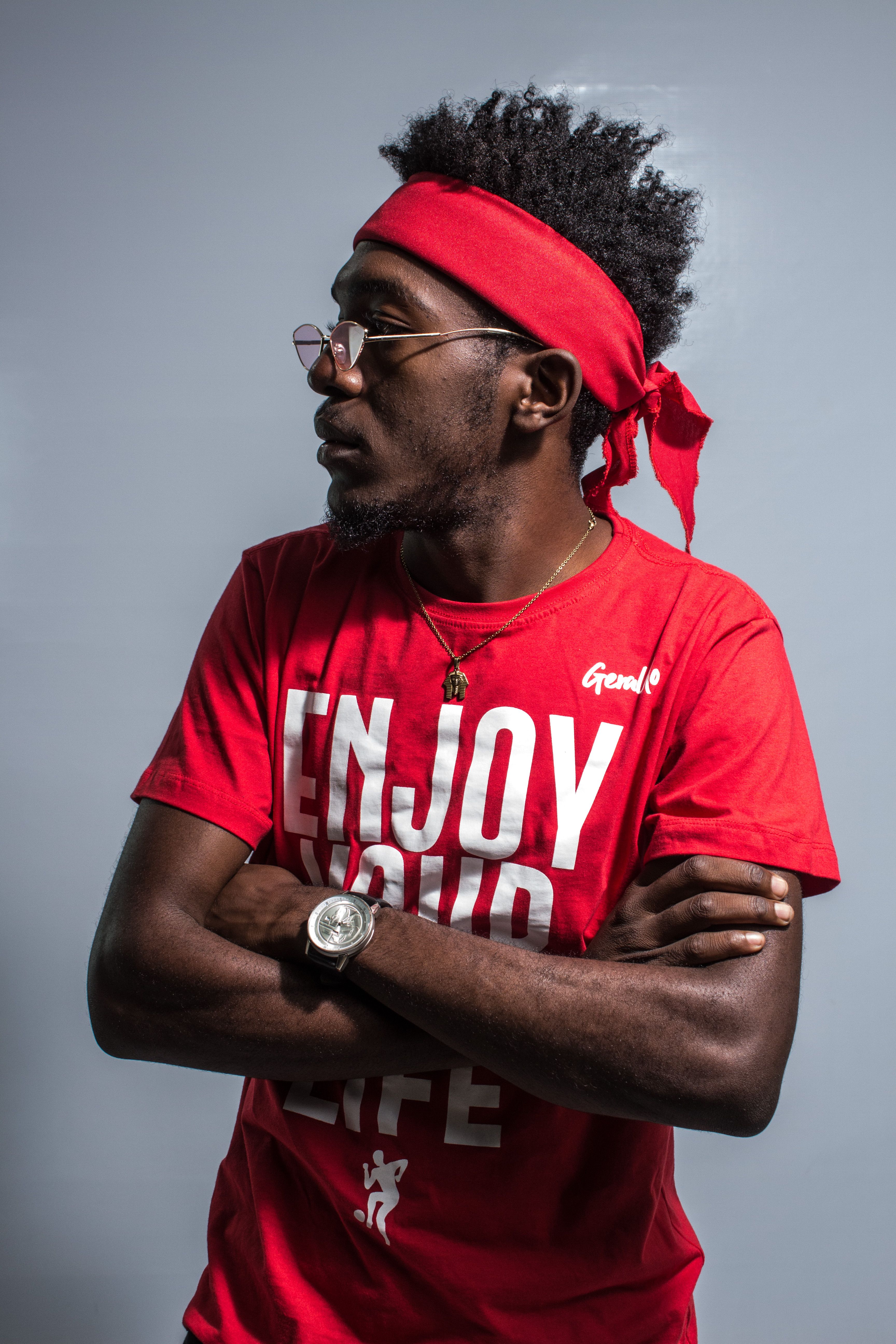 Black man with afro hair and glasses wearing a red t-shirt and bandana, side view.