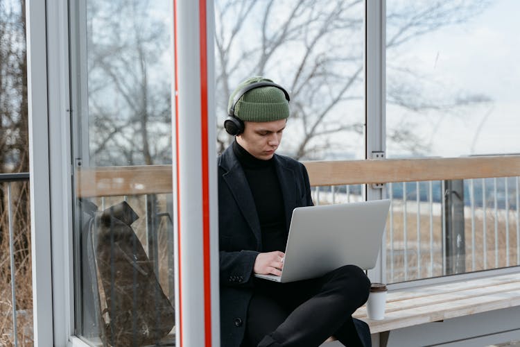 A Man Using A Laptop While Wearing Headphones