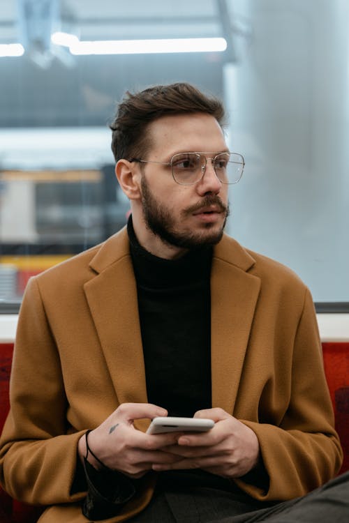 A Man in Brown Coat Using His Smartphone