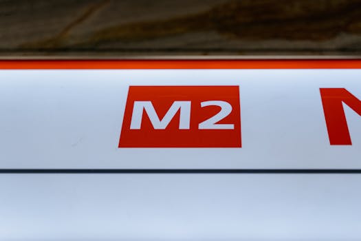 Close-up view of an illuminated red M2 sign against a white background in an urban area.