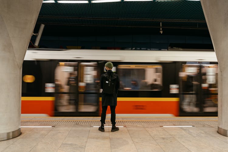 A Person Standing On The Subway Platform With A Train Passing