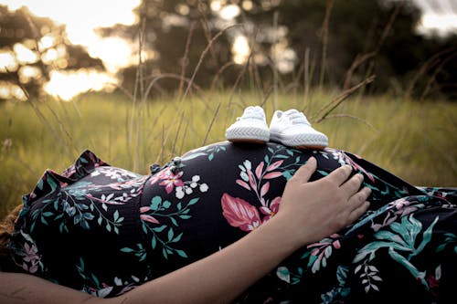 A White Baby Shoes on a Pregnant Woman's Baby Bump