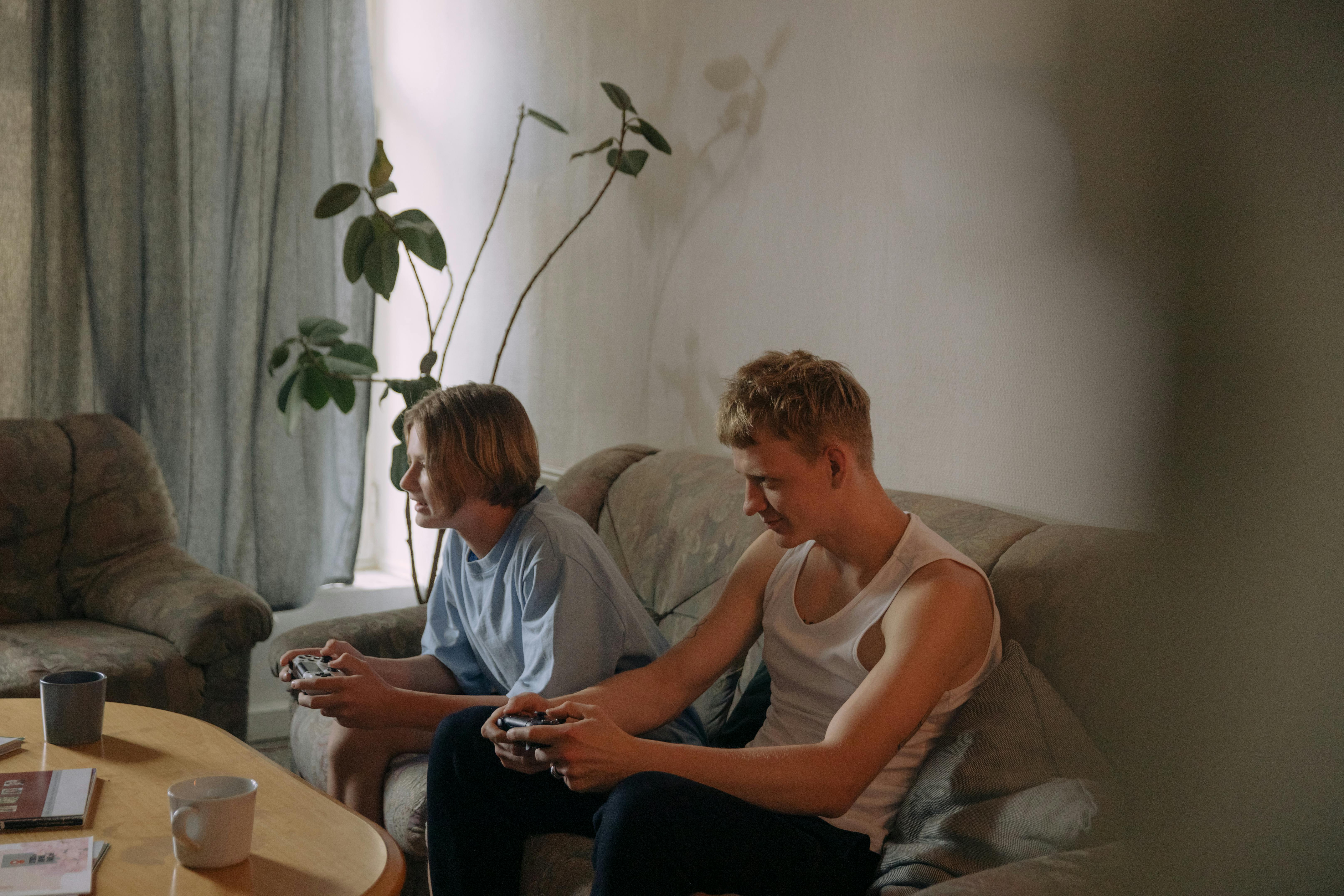 a young boys sitting on the couch while playing videogame