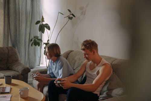 A Young Boys Sitting on the Couch while Playing Videogame
