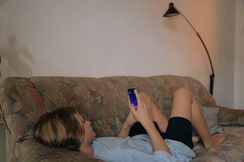 Free Woman Lying on Sofa Using Cellphone Stock Photo