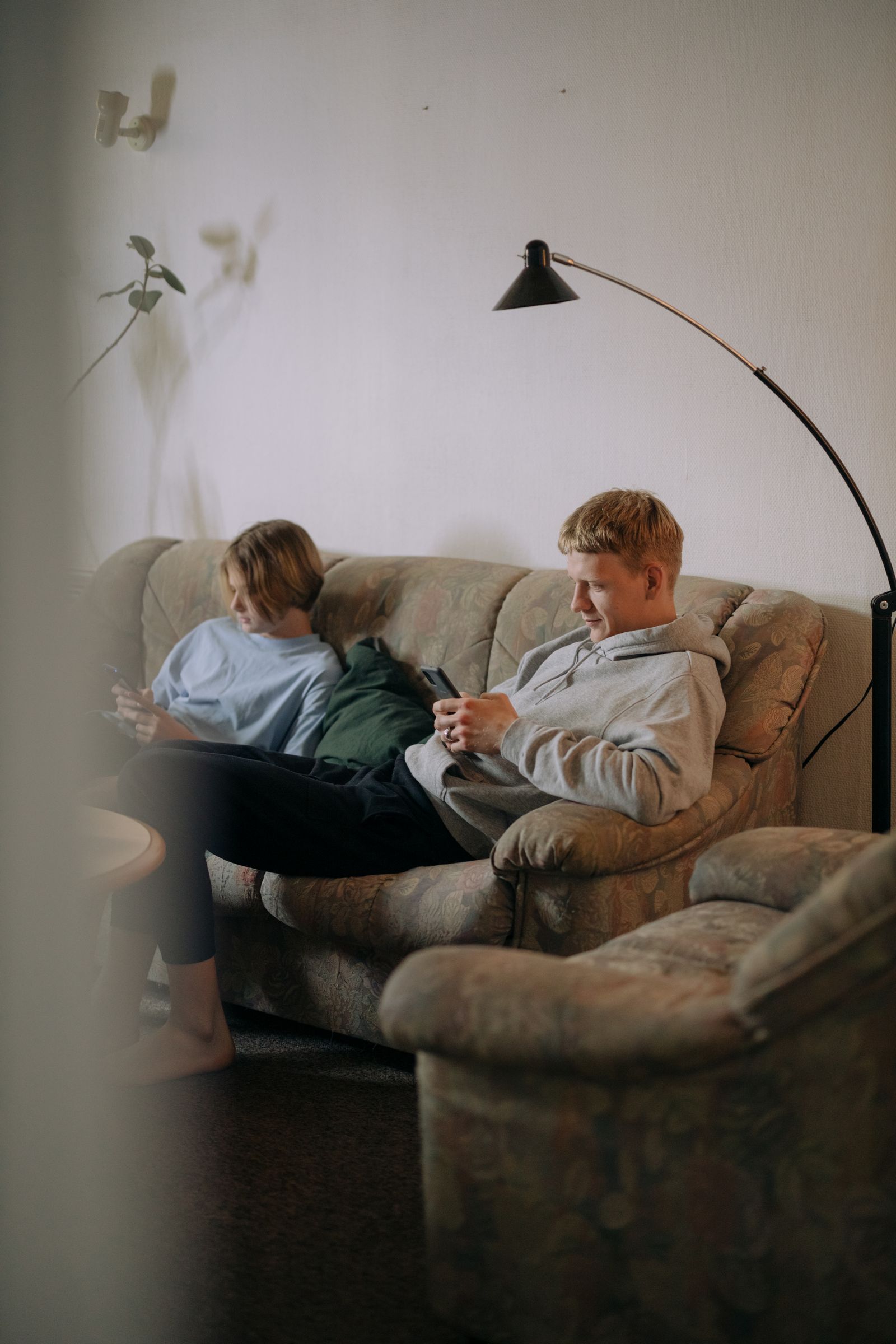 Two adults relaxing on a sofa with smartphones