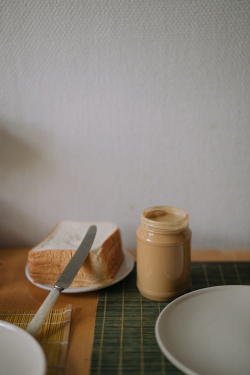 Free Peanut Butter Container beside Pile of Bread Stock Photo