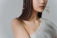 A Woman in White Sleeveless Oblique Collar Biting Baby's Breath Flowers