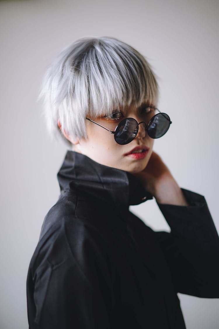 A Woman With Short Blonde Hair Wearing A Black Round Sunglasses