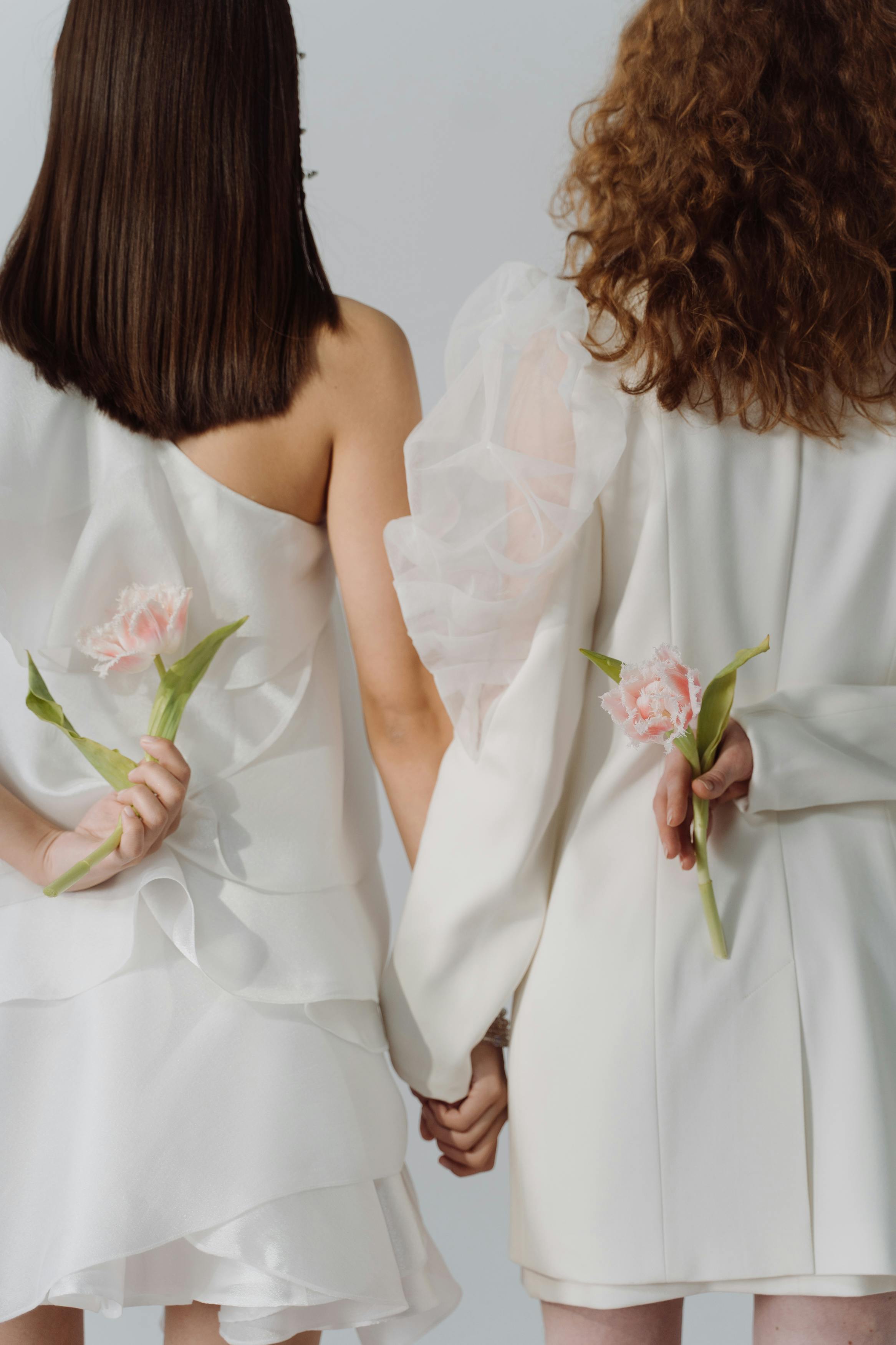 women in white dress holding pink and white flowers