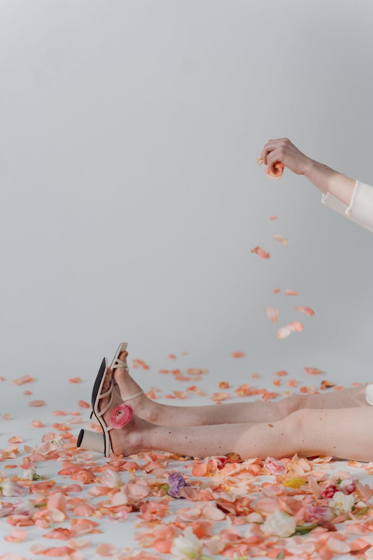 A Person Sitting On The Floor With Scattered Petals