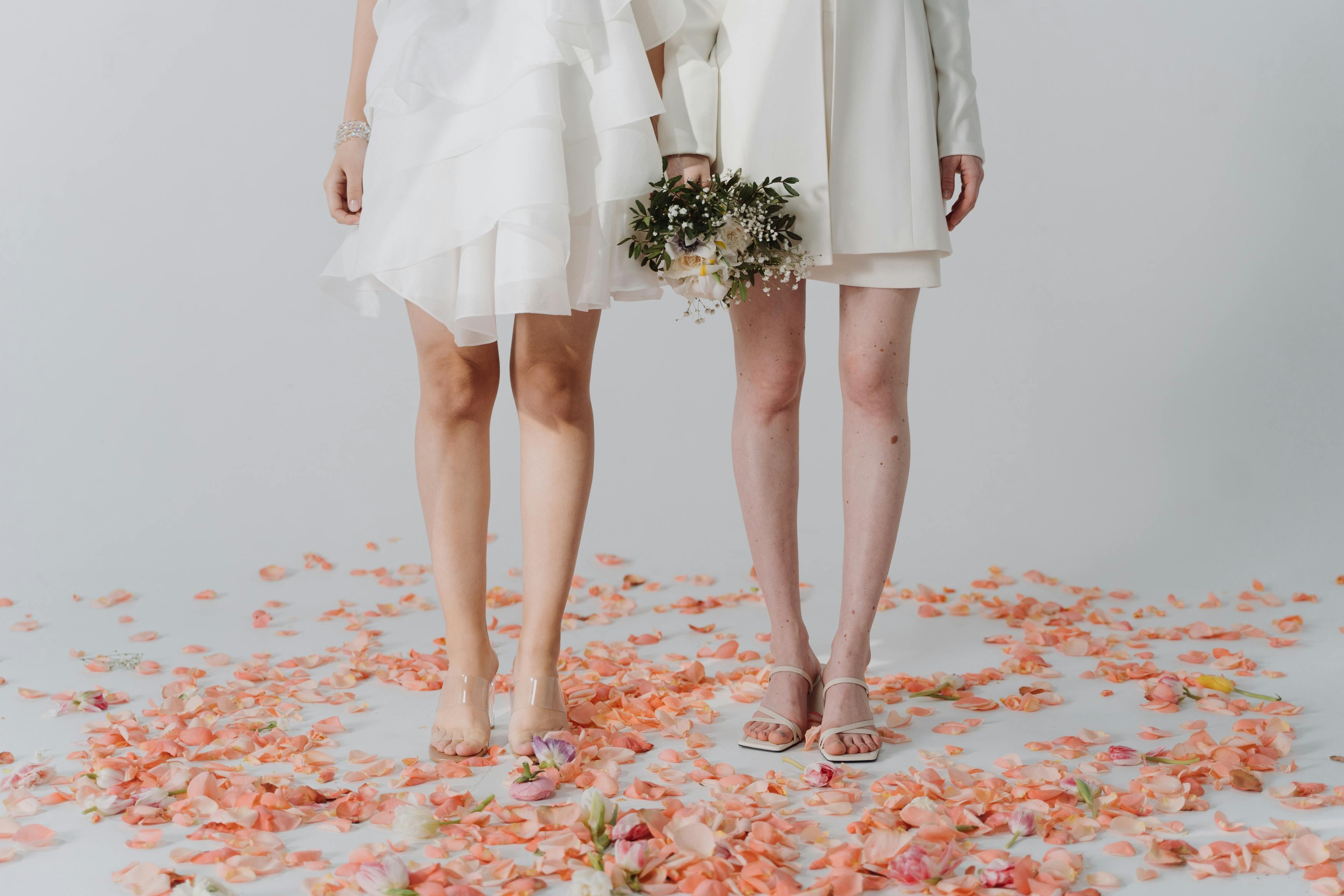 a women white dress standing on white surface with flower petals