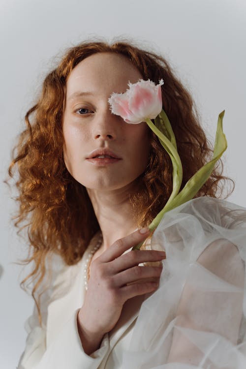 Woman in White Long Sleeve Dress Holding Pink and White Flower