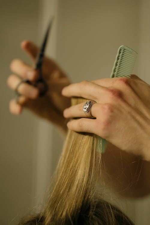 A Person Holding Scissors and Green Comb