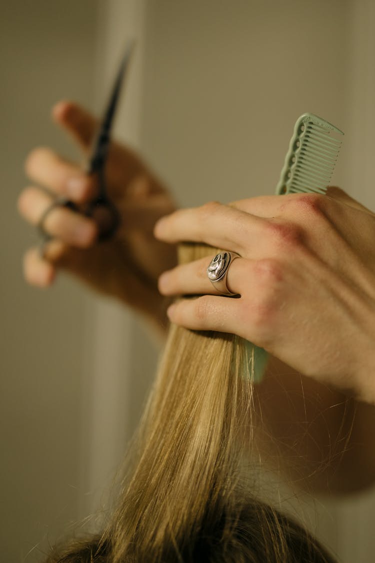 A Person Holding Scissors And Green Comb