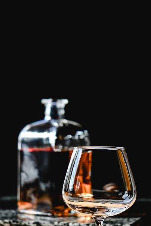 A Clear Wine Glass Beside a Bottle of a Brown Alcoholic Drink