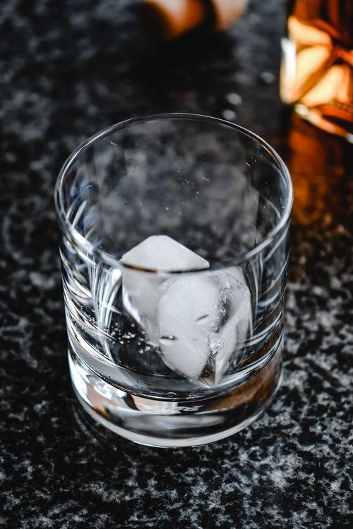 Free Elegant whiskey glass with ice cube, perfect for intimate gatherings or upscale dining settings. Stock Photo