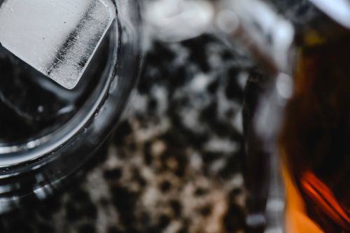 Free Artistic close-up of an ice cube in a glass on a textured surface, showcasing selective focus. Stock Photo