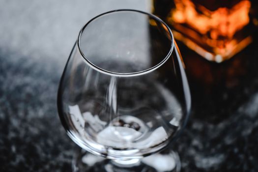 Elegant close-up of an empty snifter glass on a granite surface with a warm lighting effect.