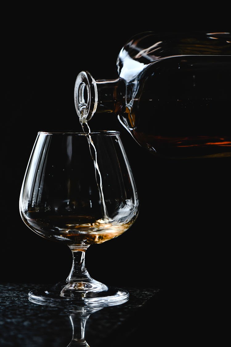 Close-Up Shot Of A Person Pouring A Liquor On A Glass