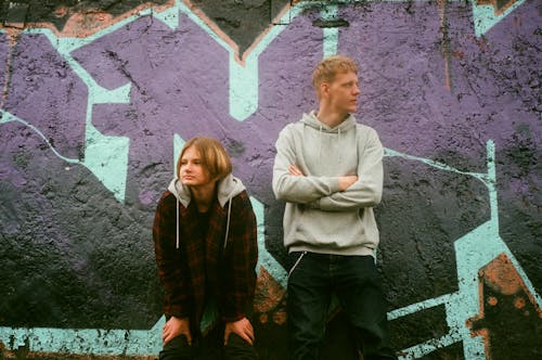 Two Teens Standing near the Graffiti Wall