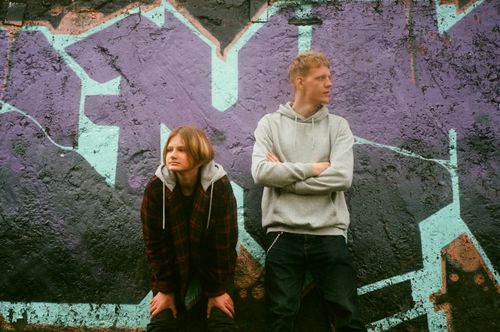 Free Two teenagers standing by a vibrant graffiti wall, showcasing street style and urban culture. Stock Photo