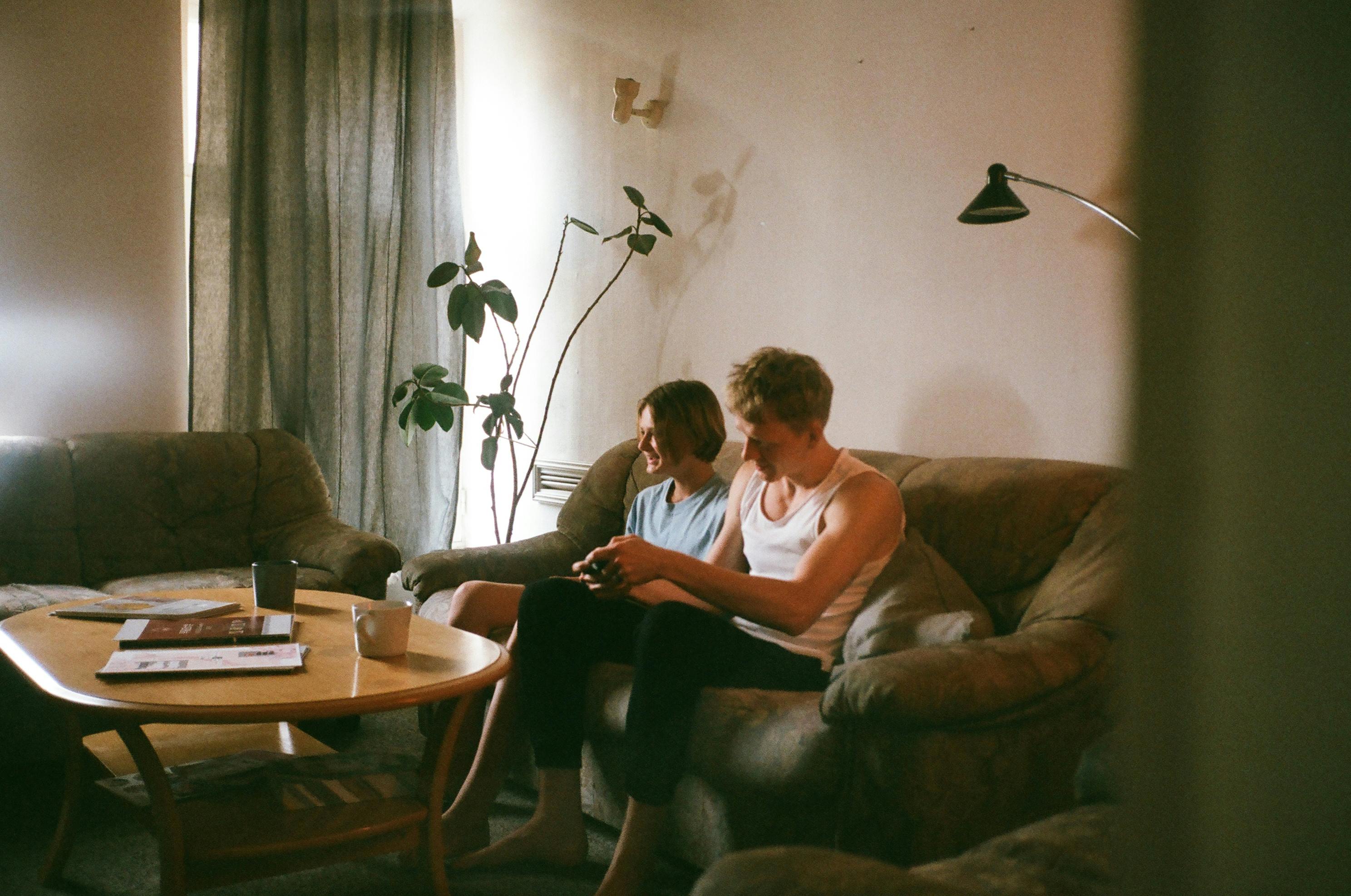 Couple enjoying a casual moment on the couch in a cozy living room with natural light.