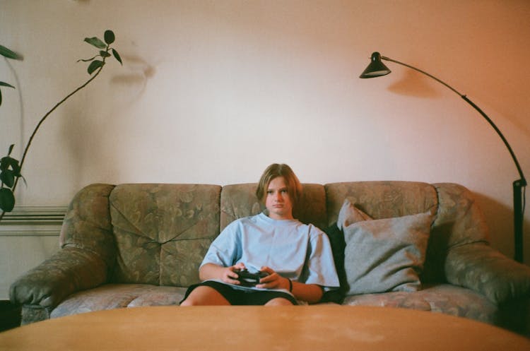 Boy Sitting On Sofa While Playing Videogame