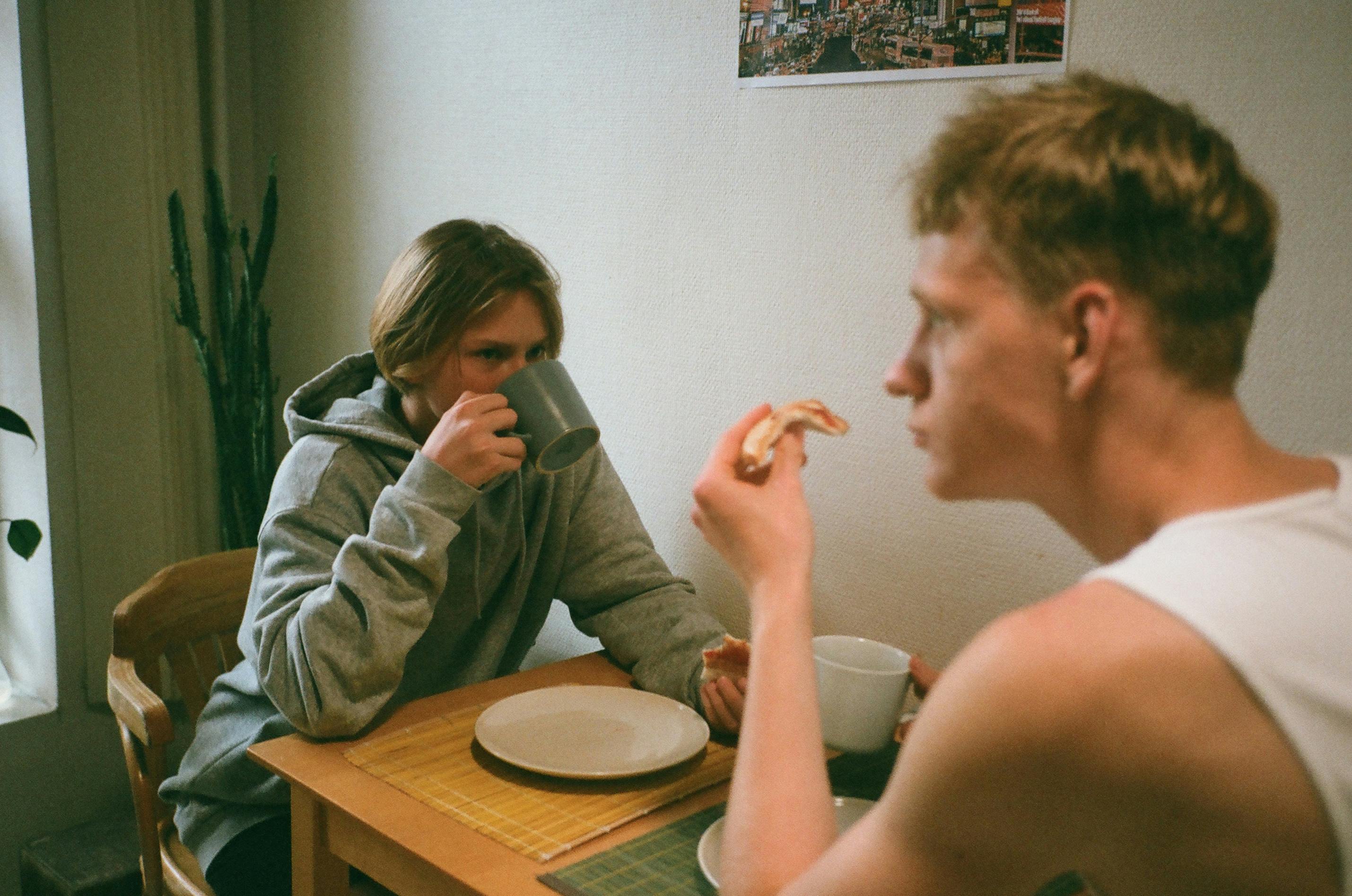 Two friends in a cozy room enjoying a simple breakfast and coffee.