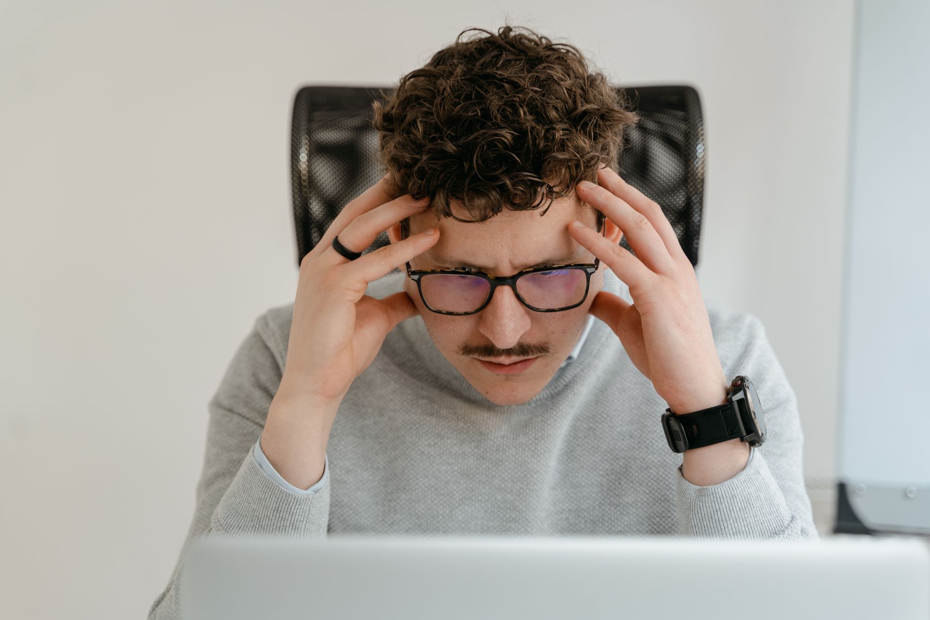 A serious businessman focusing intently on his work, using a laptop indoors.