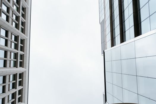 Low-angle view of modern skyscraper facades against a cloudy sky, highlighting minimalist architecture.