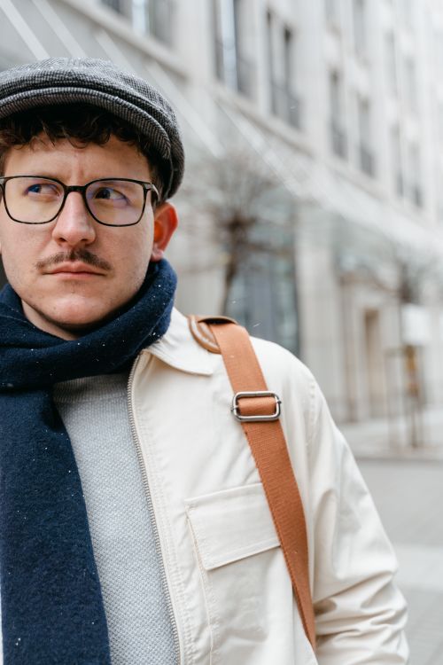 Free A thoughtful man in a flat cap and scarf on a city street, showcasing winter fashion. Stock Photo