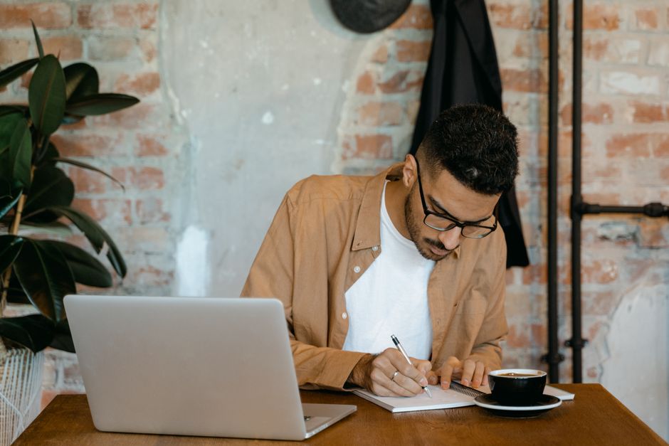 person writing laptop coffee desk focused
