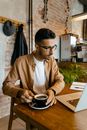 Man in Brown Dress Shirt Holding Black Ceramic Mug