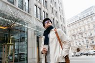 Man in Brown Coat Wearing Black Cap Standing Near Building