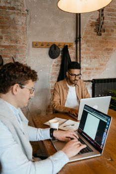 Two professionals in a modern office setting using laptops for collaborative work.