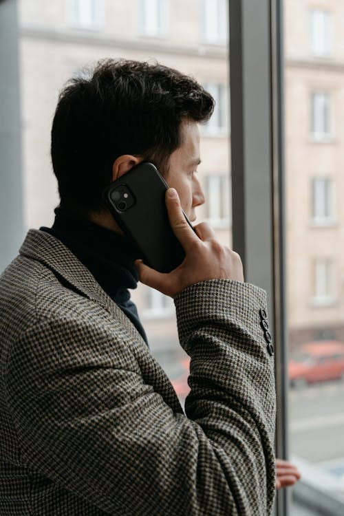 Free Man in Gray and Black Coat Holding Black Smartphone Stock Photo