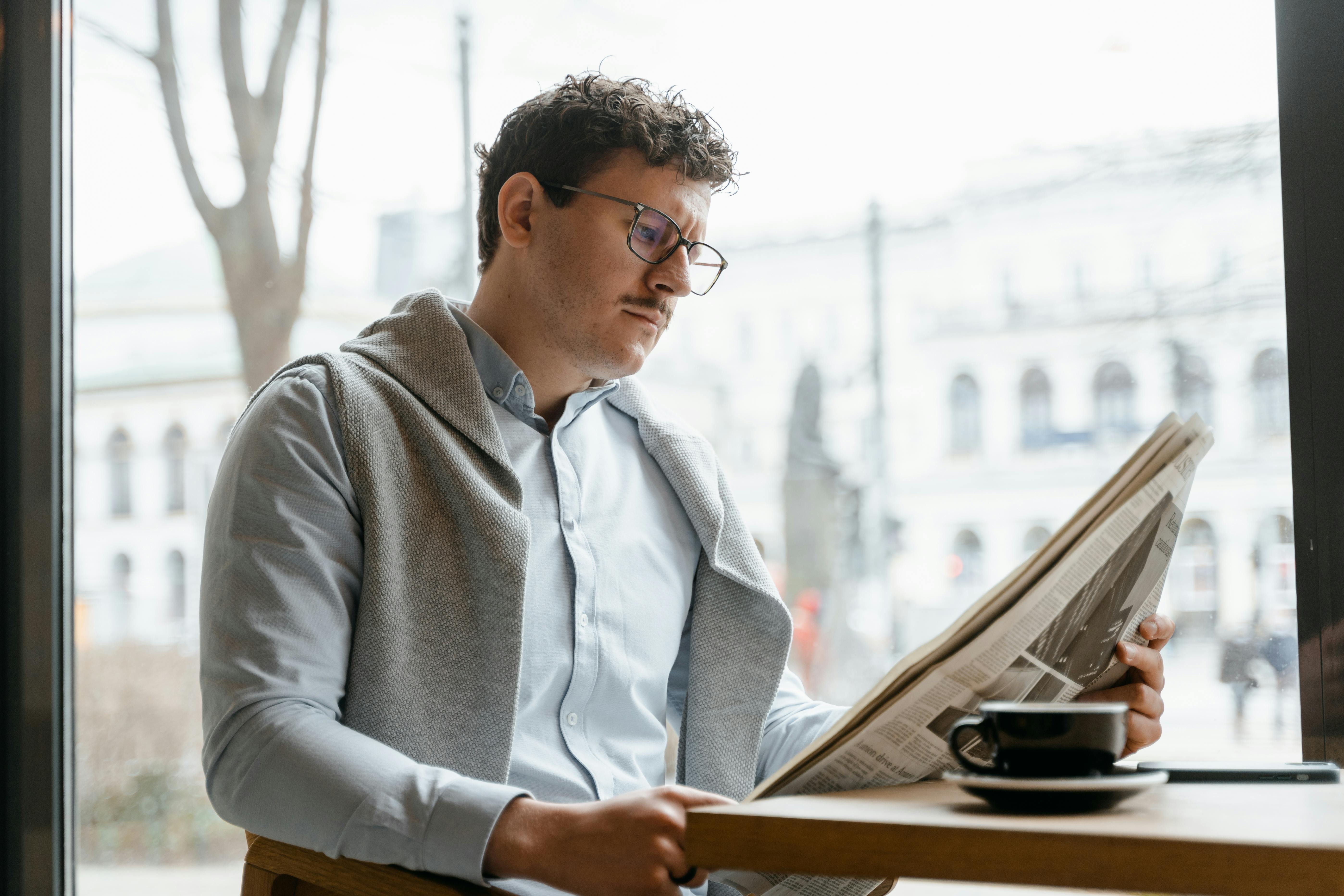 man reading a newspaper while having coffee