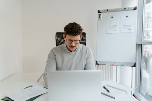 Man in Gray Sweater Working on Laptop
