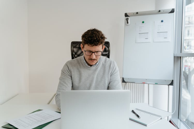 Man In Gray Sweater Working On Laptop