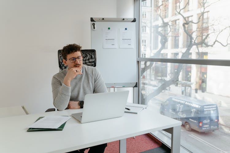 Man In Gray Sweater Wearing Eyeglasses While Working In The Office