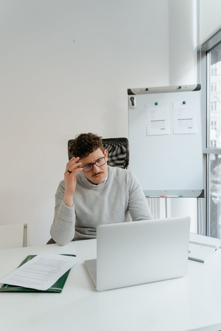 Man In Gray Sweater Wearing Eyeglasses While Working In The Office