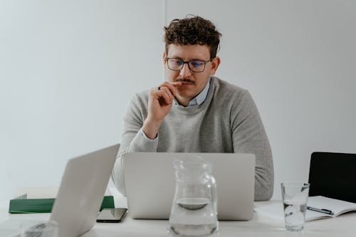A Man in a Gray Sweater and Eyeglasses using a Laptop
