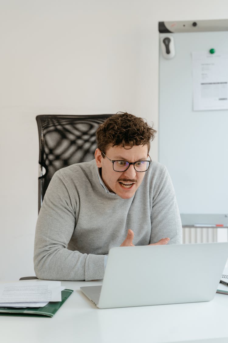 Man In Gray Sweater Wearing Eyeglasses While Working In The Office