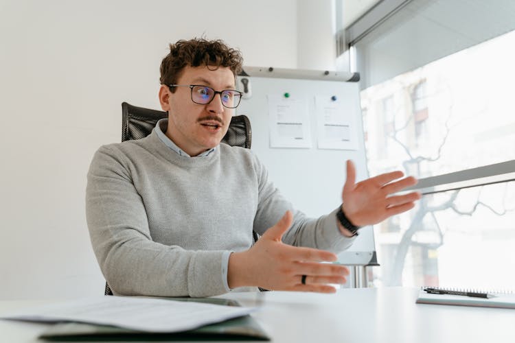 Man In Gray Sweater Wearing Eyeglasses While Working In The Office