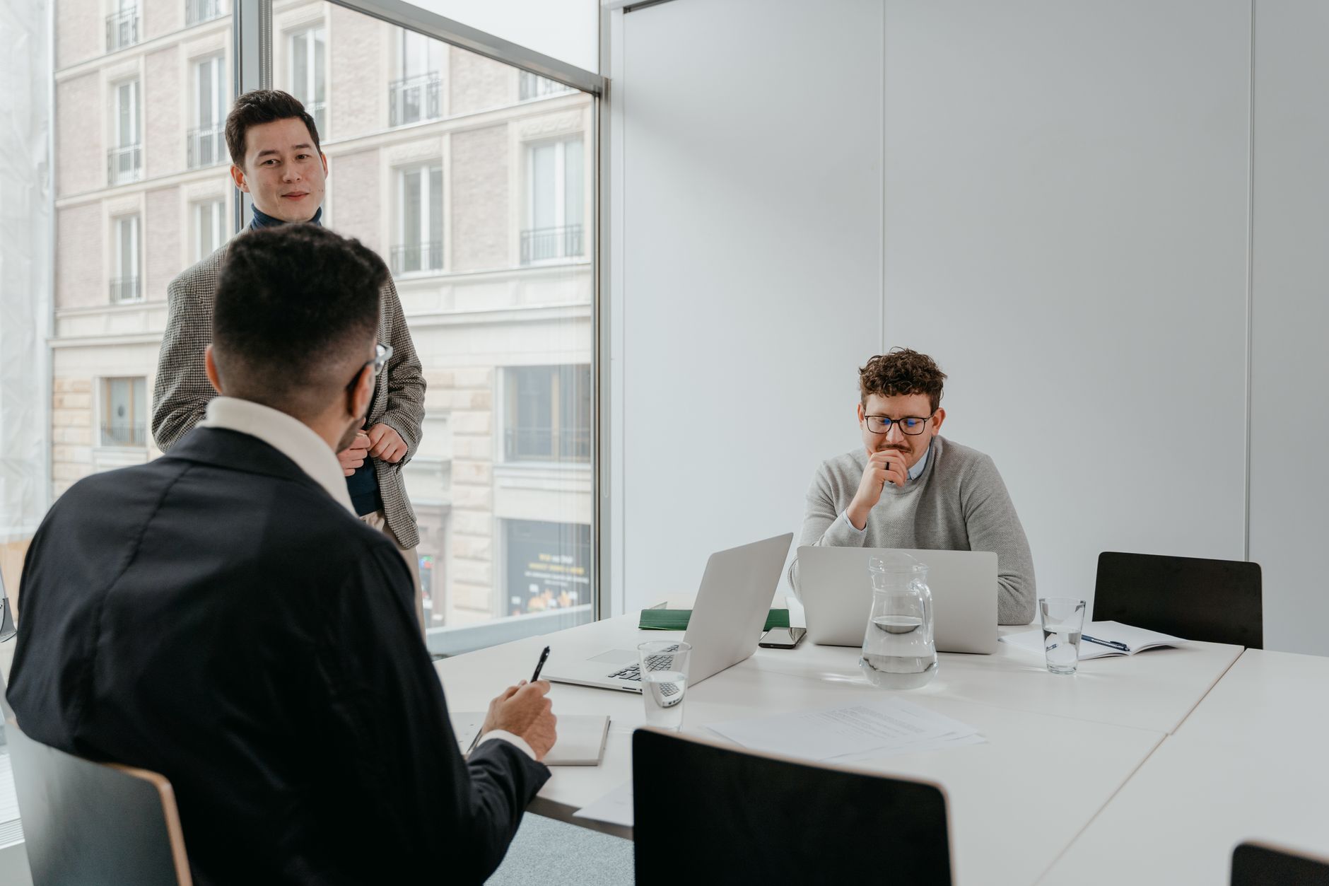 Three business professionals discuss strategies in a bright, modern office setting.