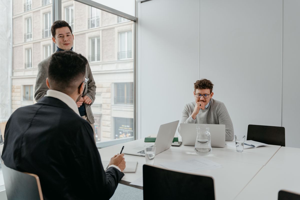 Three business professionals discuss strategies in a bright, modern office setting.