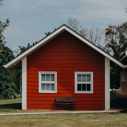 Free A vibrant red bungalow facade with windows and a bench in a serene outdoor setting in the Philippines. Stock Photo